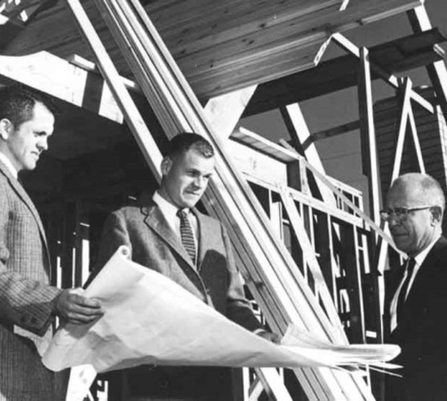Black and white photo showing Ayres founders looking at construction plans