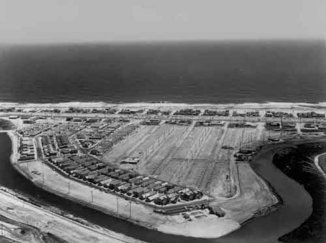 Black and white photo of a town being constructed next to the ocean
