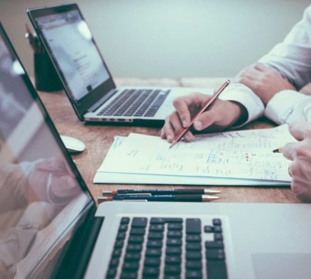 Two people working at laptops and looking at documents